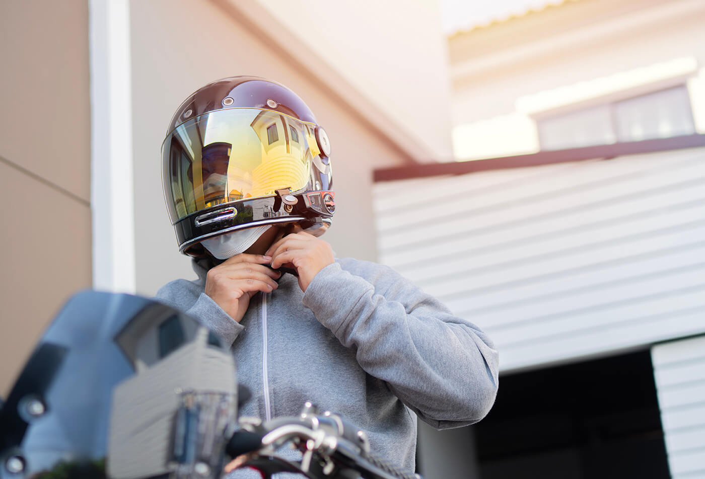 Motorradfahrer schließt vor der Fahrt den Kinnriemen seines Integralhelms mit verspiegeltem Visier
