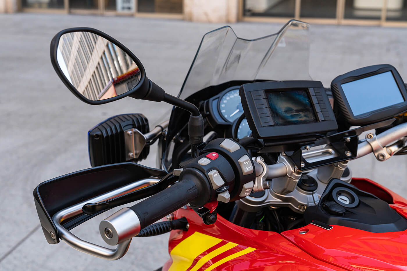 Motorradlenker mit montiertem Navi-Display neben Cockpit, Windschild und Rückspiegel in der Nahaufnahme